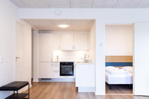 a kitchen with white cabinets and a bed in a room at Hotel Aurora Apartments in Nuuk