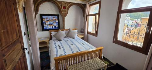 a bedroom with a bed in a room with a window at Dar Nomads in Chefchaouen