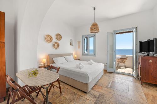 a bedroom with a bed and a table and a television at Sea view rooms in kardiani by TinosStay in Kardhianí