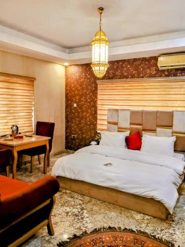 a bedroom with a large white bed and a desk at Zamin Suites in Abuja