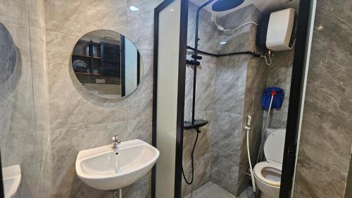 a bathroom with a sink and a mirror and a toilet at SkyBreeze Sentraland in Medan