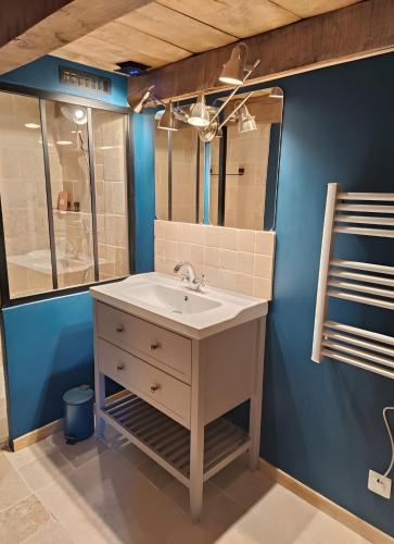 a bathroom with a sink and a blue wall at Gîte Escapade À La Voreille in Mazirat