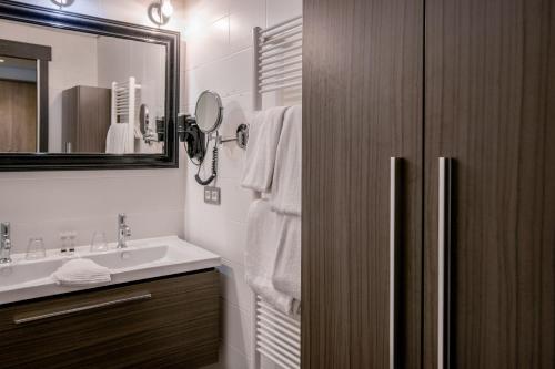 ein Badezimmer mit Waschbecken und Spiegel in der Unterkunft Blanckthys Hotel Voeren in Voeren