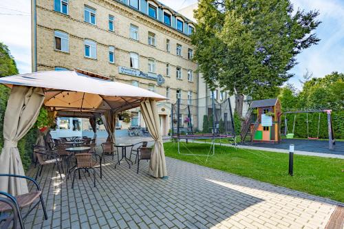 a patio with tables and chairs and an umbrella at RigaApartment SoNaDA Self Check-in Aparthotel, Center, Private Parking in Riga