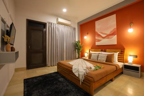 a bedroom with a large bed with orange walls at Studio Serviced Apartments near Fortis Hospital in Gurgaon