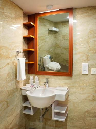 a bathroom with a sink and a mirror and a toilet at Hotel Sea Blue MALLAPPALLY in Vennikulam