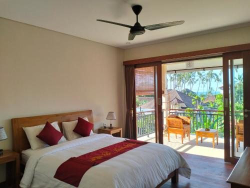 a bedroom with a bed with a ceiling fan and a balcony at Le Jardin in Amed