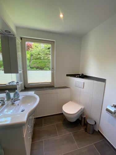 a bathroom with a toilet and a sink and a window at Extertal-Ferienpark - Sonnenhügel in Extertal