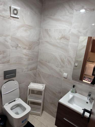 a bathroom with a toilet and a sink and a mirror at Studio Luxe Bouznika Beach Piscine, Clim, Wi-Fi ,Check in 24h Plage 5 min in Bouznika
