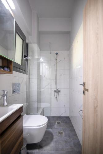 a white bathroom with a toilet and a shower at Sea Breeze Stay 1 in Salamina