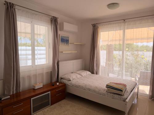 a bedroom with a bed and windows and a desk at Villa Andy-350 m from the beach in Larnaca