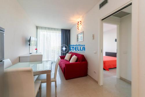 a living room with a red couch and a bedroom at Condominio Mimose in Eraclea Mare