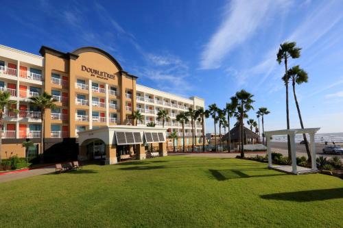a hotel with a lawn in front of a building at DoubleTree by Hilton Galveston Beach in Galveston
