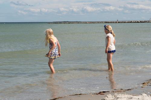 two girls standing in the water at the beach at Frederikshavn Nordstrand Camping & Cottages in Frederikshavn