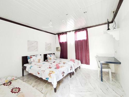 a bedroom with two beds and a table and a window at OYO 1214 Cherry Travellers Inn in San Jose de Buenavista