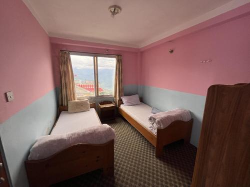 a small room with two beds and a window at Subhechchha Hotel in Charikot