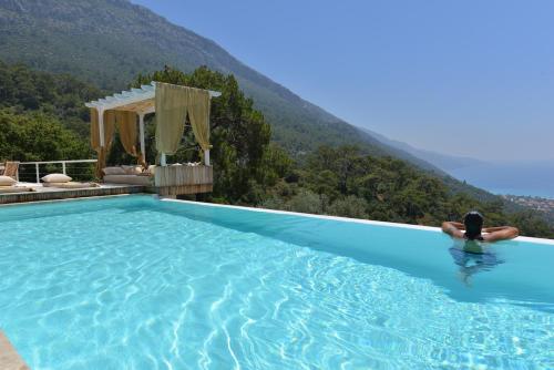 a person in a swimming pool with a mountain in the background at Ölüdeniz Loft - Adults Only in Oludeniz