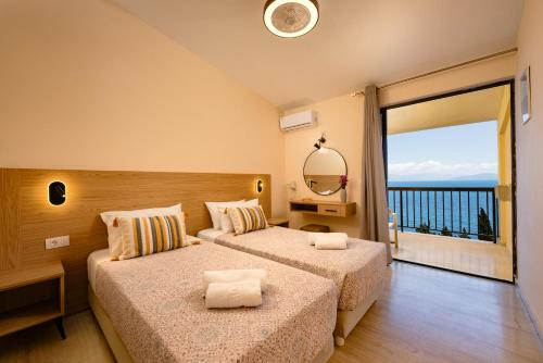 a hotel room with two beds and a large window at Siora Leni Hotel in Benitses