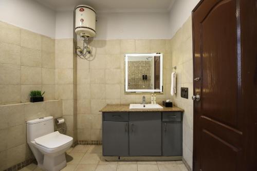 a bathroom with a toilet and a sink and a mirror at BedChambers Serviced Apartments, Sushant Lok in Gurgaon