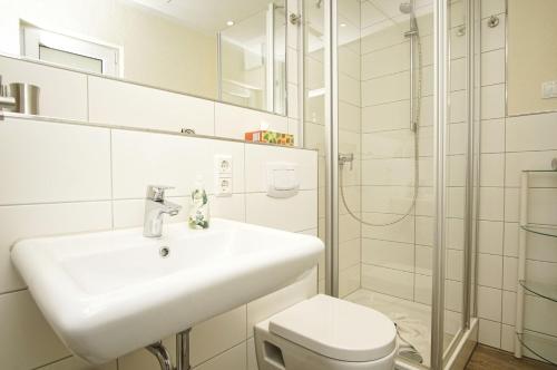 a white bathroom with a sink and a shower at Bungalow Hanseatchen in Baabe