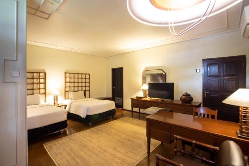 a bedroom with two beds and a desk and a television at Mesra International Hotel in Samarinda