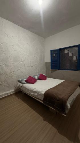a bedroom with a bed with two red pillows at Casa Colina in Ouro Preto