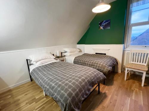 two beds in a room with a green wall at Swan Lodge in Swanage