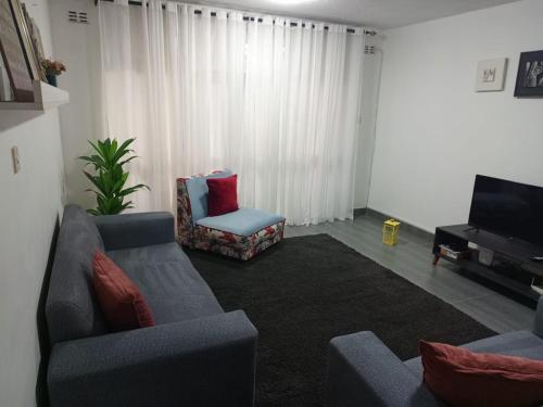 a living room with a couch and a chair and a television at Apartment 8, 7373A, Mtedza Rd in Lusaka
