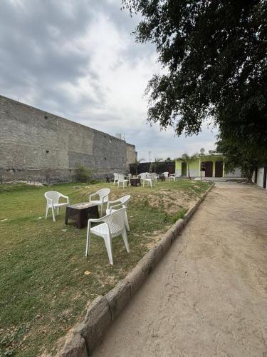 a group of white chairs and tables in a field at Palm resort in Greater Noida