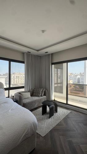 a bedroom with a bed and a couch and windows at M Residence in Dhahran