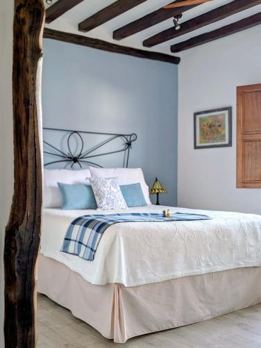 a bedroom with a bed with white sheets and blue pillows at El Jardín del Laurel - only adults - in Candelario