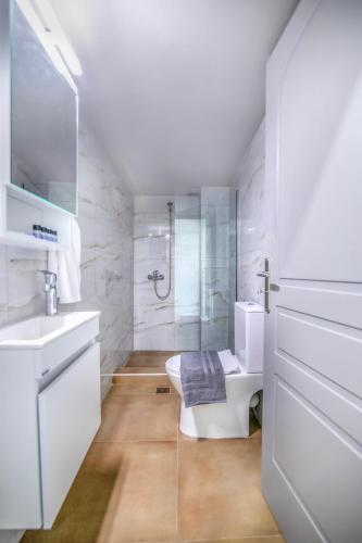 a white bathroom with a toilet and a sink at Sea Breeze Stay 2 in Salamina