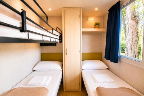 two beds in a small room with a window at Bungalow Resort Ameglia in Ameglia