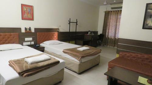 a bedroom with two beds and a desk in it at The Boulevard Hotel in Jamshedpur