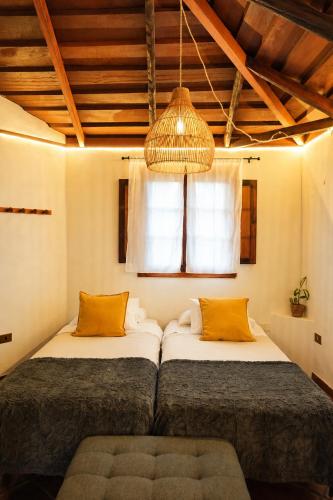 a bedroom with two beds and a chandelier at La Paredita Casa Guimar in Tanque