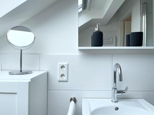 a white bathroom with a sink and a mirror at Fewo Diemelsee 5 in Heringhausen
