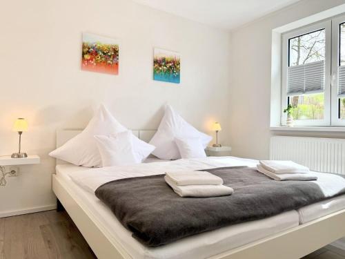 a white bedroom with a large bed with two pillows at Fewo Diemelsee 4 in Heringhausen