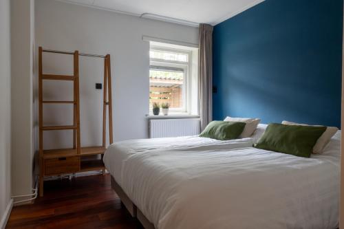 a bedroom with a large bed with a blue wall at De Bosberg Villa in Appelscha