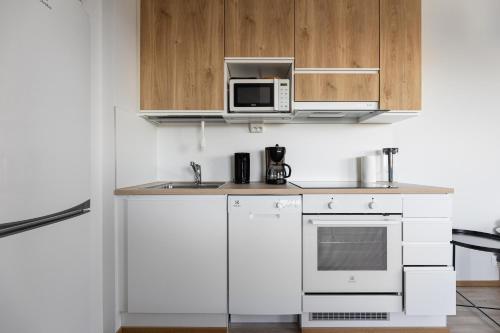 a white kitchen with a microwave and a sink at Spot Apartments Oulu in Oulu