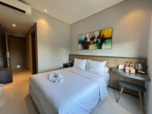 a bedroom with a large white bed and a table at Front One Hotel Gresik in Panggang