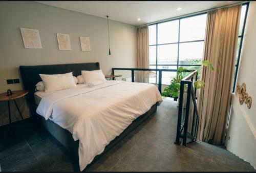 a bedroom with a large bed and a balcony at Wolu Designer Loft - Private Pool & Tropical Garden, Canggu in Tumbak Bayuh