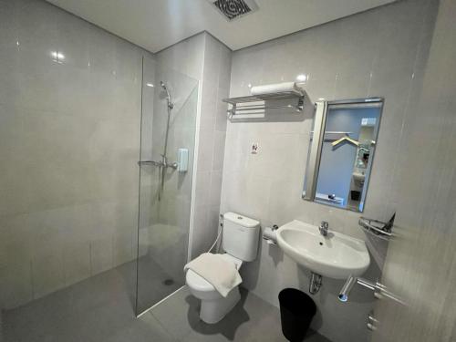 a bathroom with a toilet and a sink and a shower at Front One Hotel Gresik in Panggang