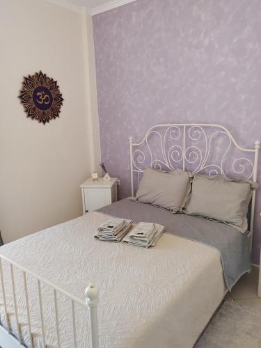 a bedroom with a white bed with a purple wall at Emotion Apartments in Asprovalta