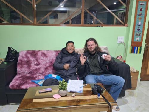 two men sitting on a couch with a coffee table at TN's Basecamp Hostel in Tawang