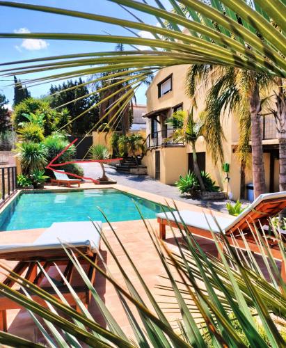 a swimming pool with palm trees and a building at Villamasai "Un pedacito de África en Valencia" in Valencia