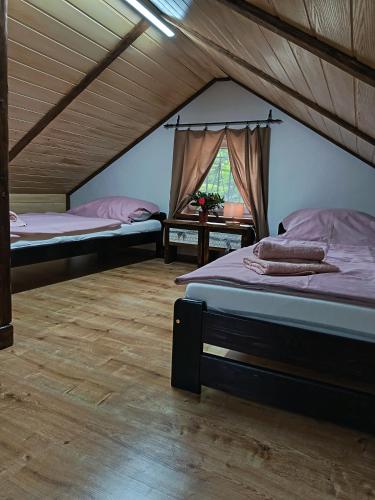 two beds in a attic room with a window at Chata Pohodička in Banský Studenec