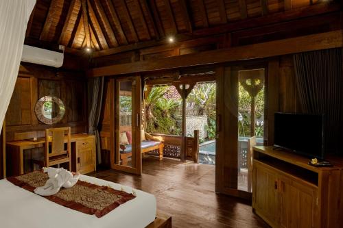 a bedroom with a bed and a television in a room at Bumbung Sari Villa in Ubud