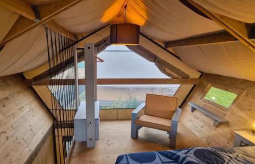 a room with a bed and a chair in a tent at Calasole Glamping in Pescia Romana