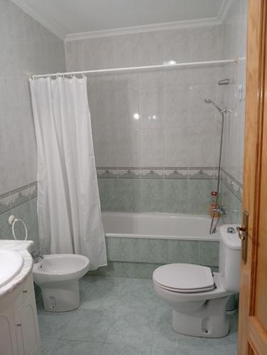 a bathroom with a toilet and a tub and a sink at Apartamento manchego Macrina in Villarta de San Juan
