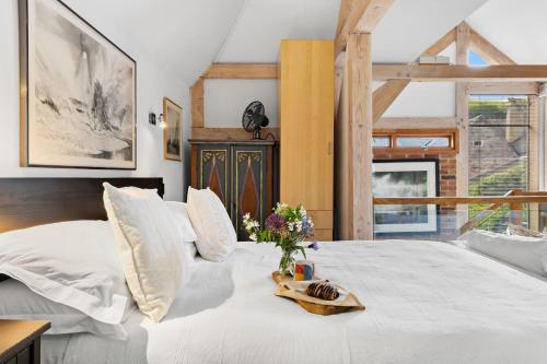 a white bed with a vase of flowers on it at Barberry Brook - Swimming pool acces in Dittisham